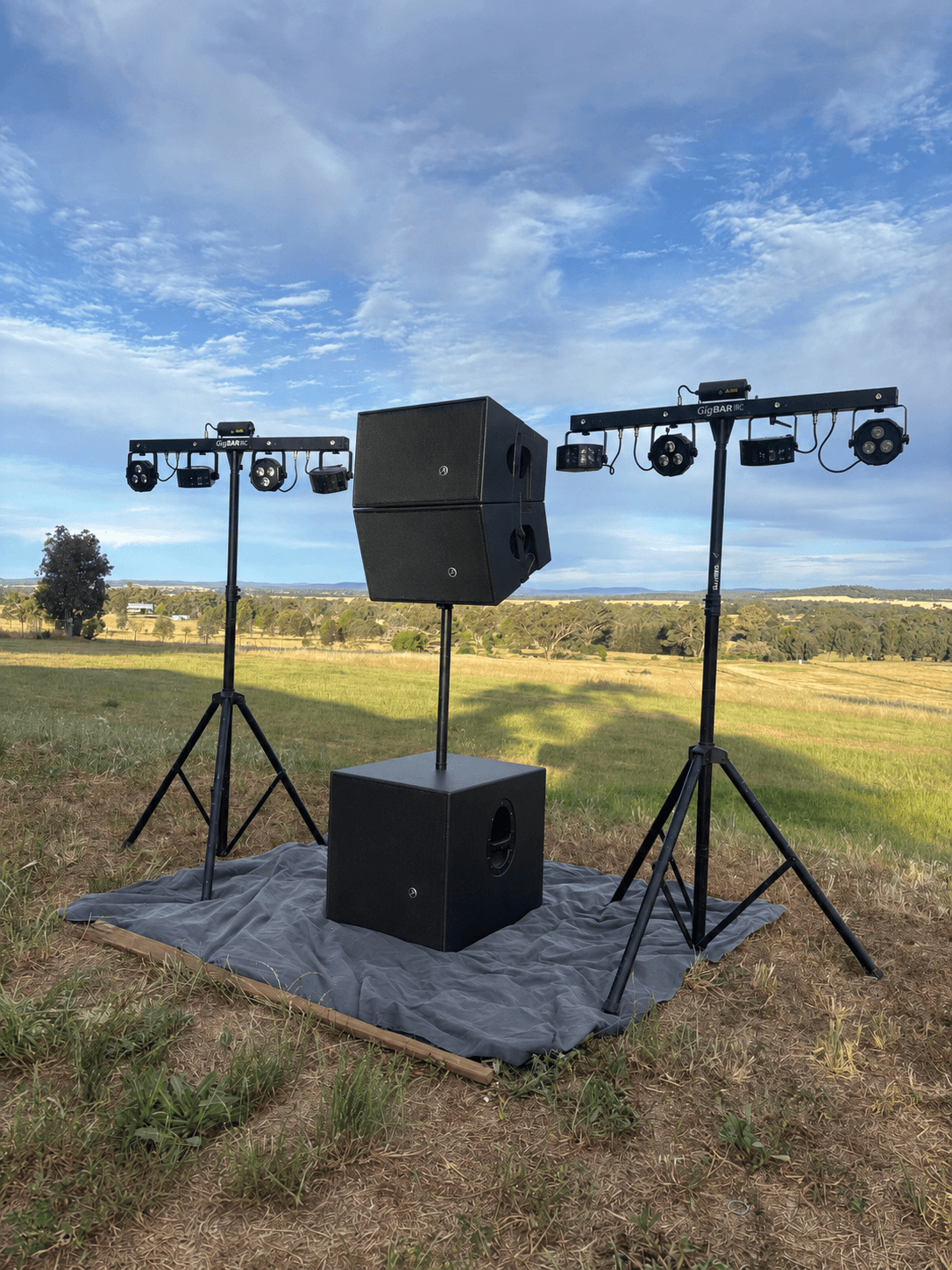Centre-stacked Mackie tops on a subwoofer flanked by two GigBAR lighting stands