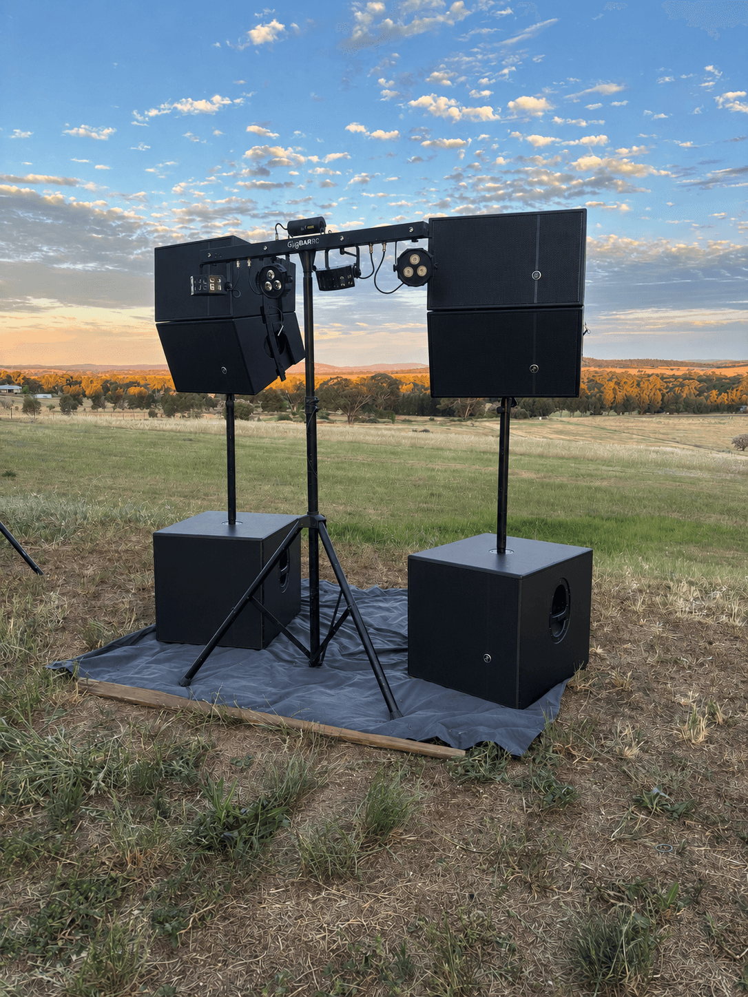 Large concert rig with stacked Mackie HDA tops, subwoofers and GigBAR lighting at sunset