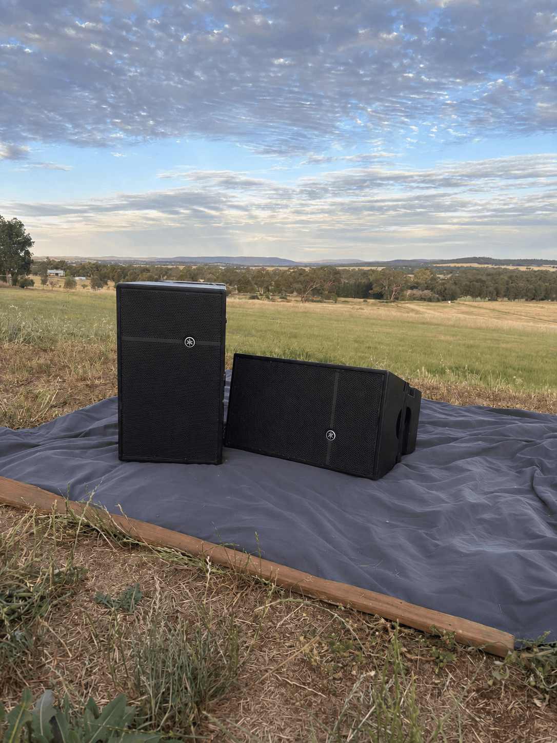 Pair of Mackie HDA-12 tops on a stage mat in a paddock