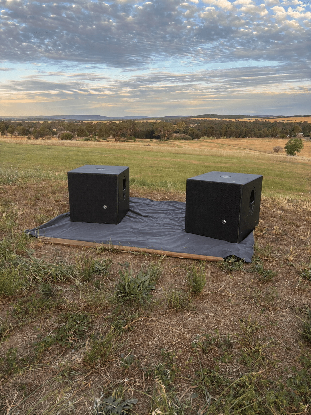 Two Mackie subwoofers side by side on a stage mat