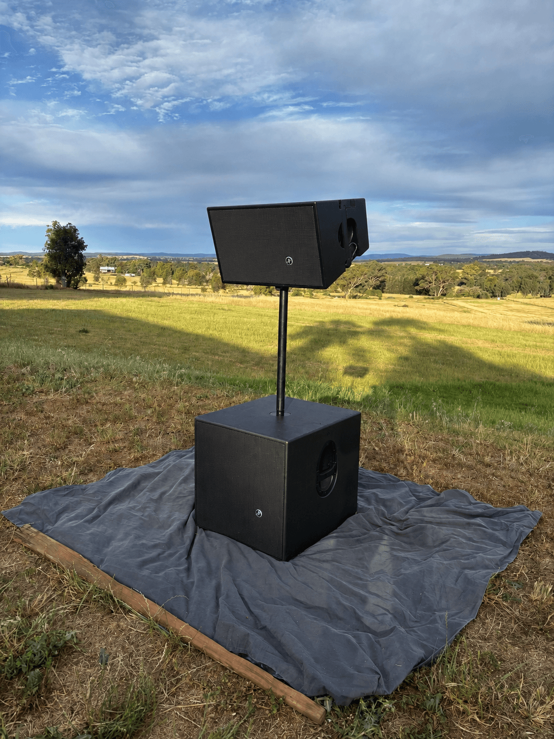Single Mackie HDA top mounted on a subwoofer on a pole at sunset
