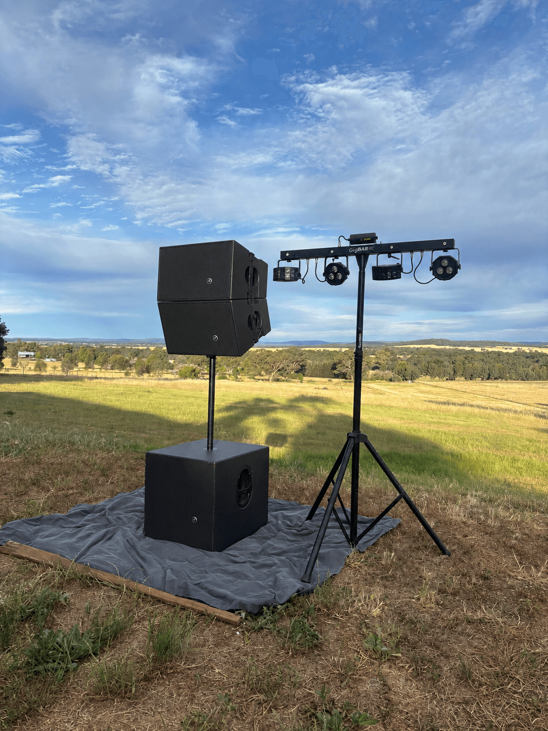 Stacked Mackie HDA tops on a subwoofer next to a GigBAR lighting stand